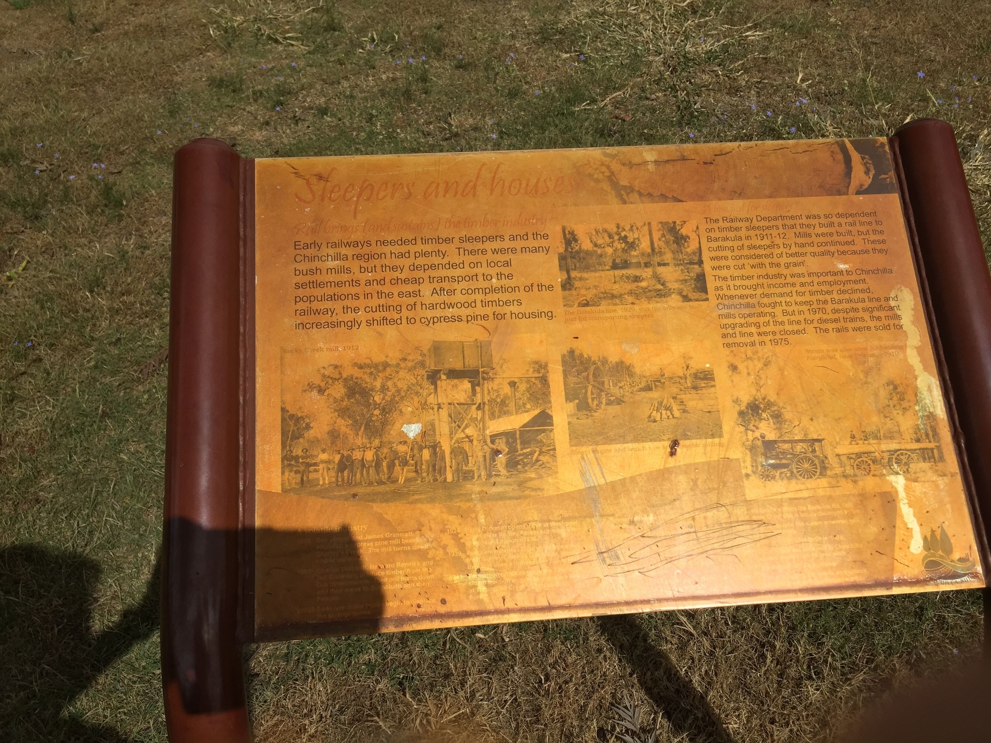Una placa histórica con texto y fotografías que narran la historia de durmientes de ferrocarril y viviendas en la región de Chinchilla.