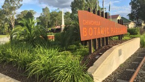 Señal de Chinchilla Botanical Parkland con un camino y follaje en primer plano.