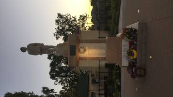 A statue in a public square with a plaque and flowers.