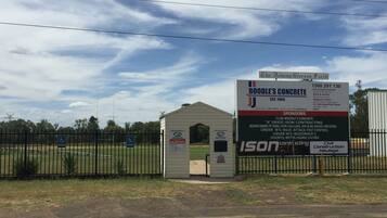 A construction site with a sign for Boodle's Concrete, a small shed, and a fenced area with handicap parking signs.