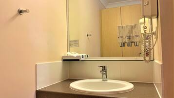 A bathroom with a sink, mirror, and hand soap dispenser.