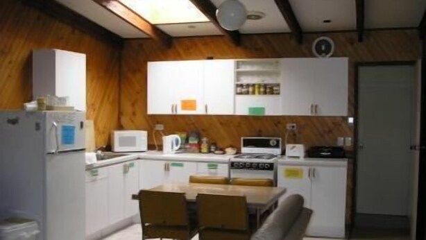 Una cucina compatta con mobili bianchi, un fornello, un forno a microonde e un'area pranzo con tavolo e sedie.