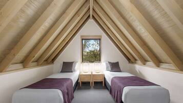 A room with two beds, a window, and wooden beams.