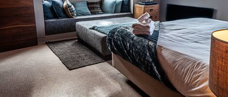 A bedroom with a bed, a TV, a window, a sofa, and a nightstand.