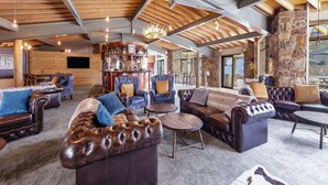 A spacious living area with leather sofas, a bar area, and a stone accent wall.
