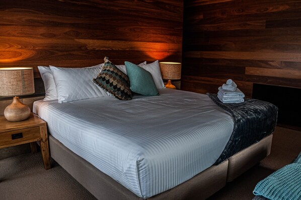 A neatly made bed with a striped bedspread, two pillows, and a folded towel on the side.