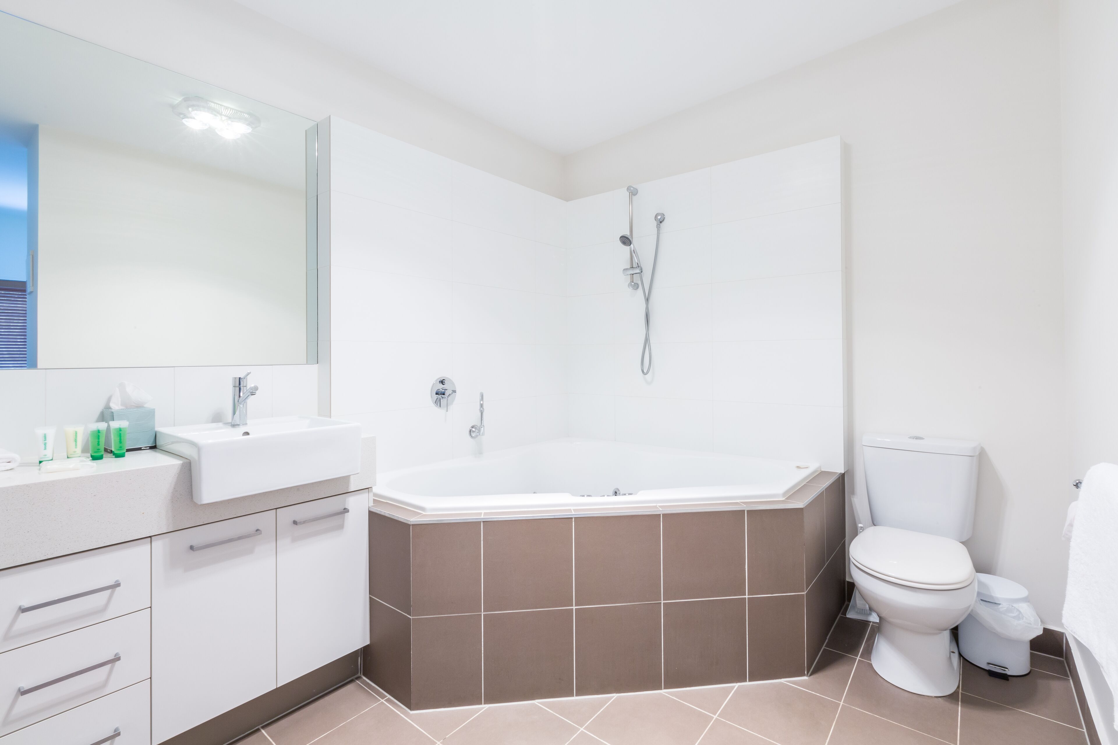Un bany modern amb una banyera gran, un vàter i un lavabo amb un mirall a sobre.