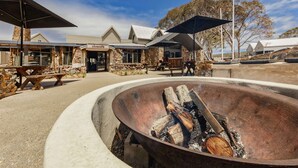 An outdoor seating area with a fire pit, stone walls, and umbrellas.