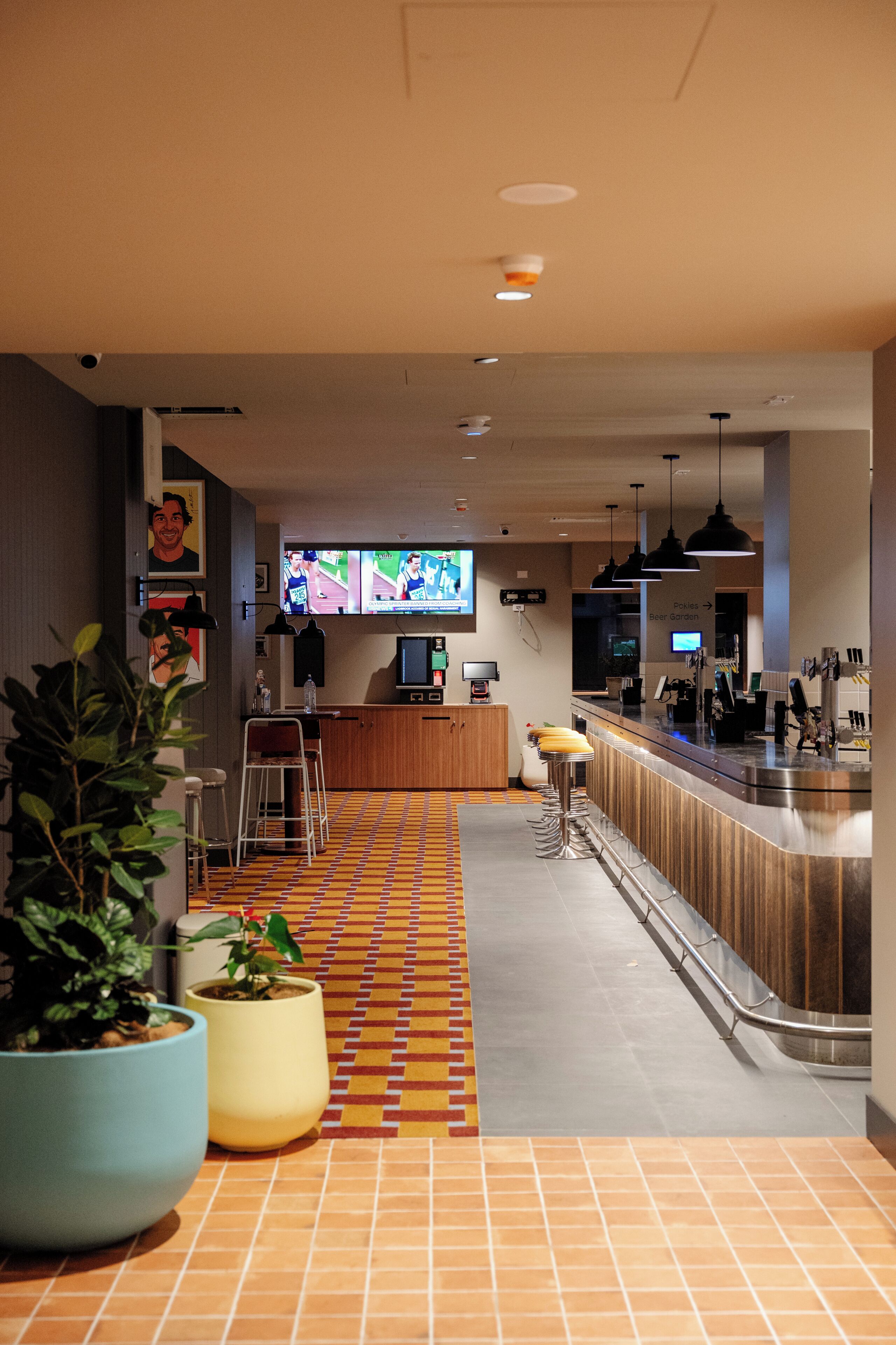 A modern bar area with a tiled floor, bar stools, and a counter.
