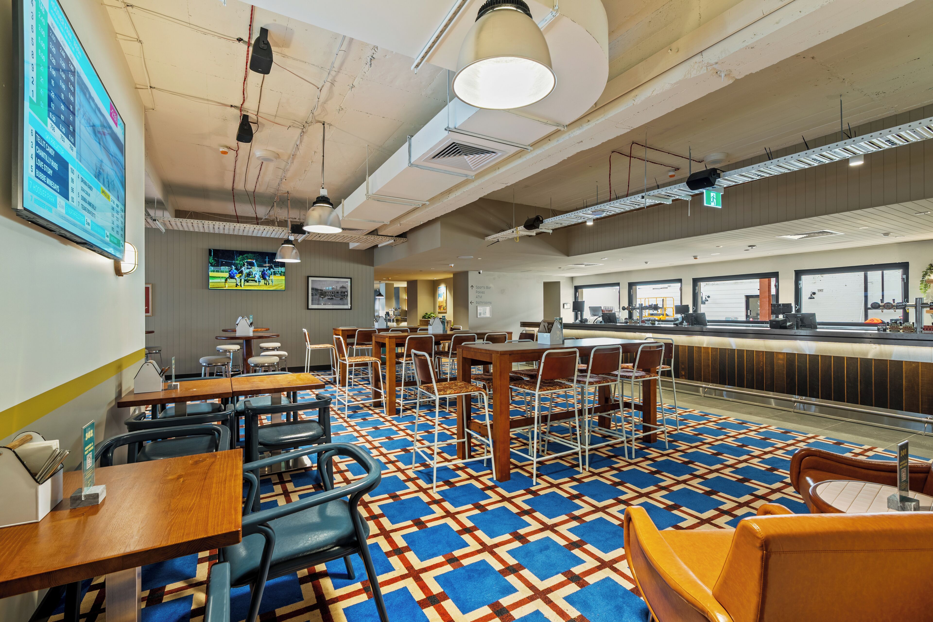 A restaurant with tables and chairs, a counter, and a patterned floor.