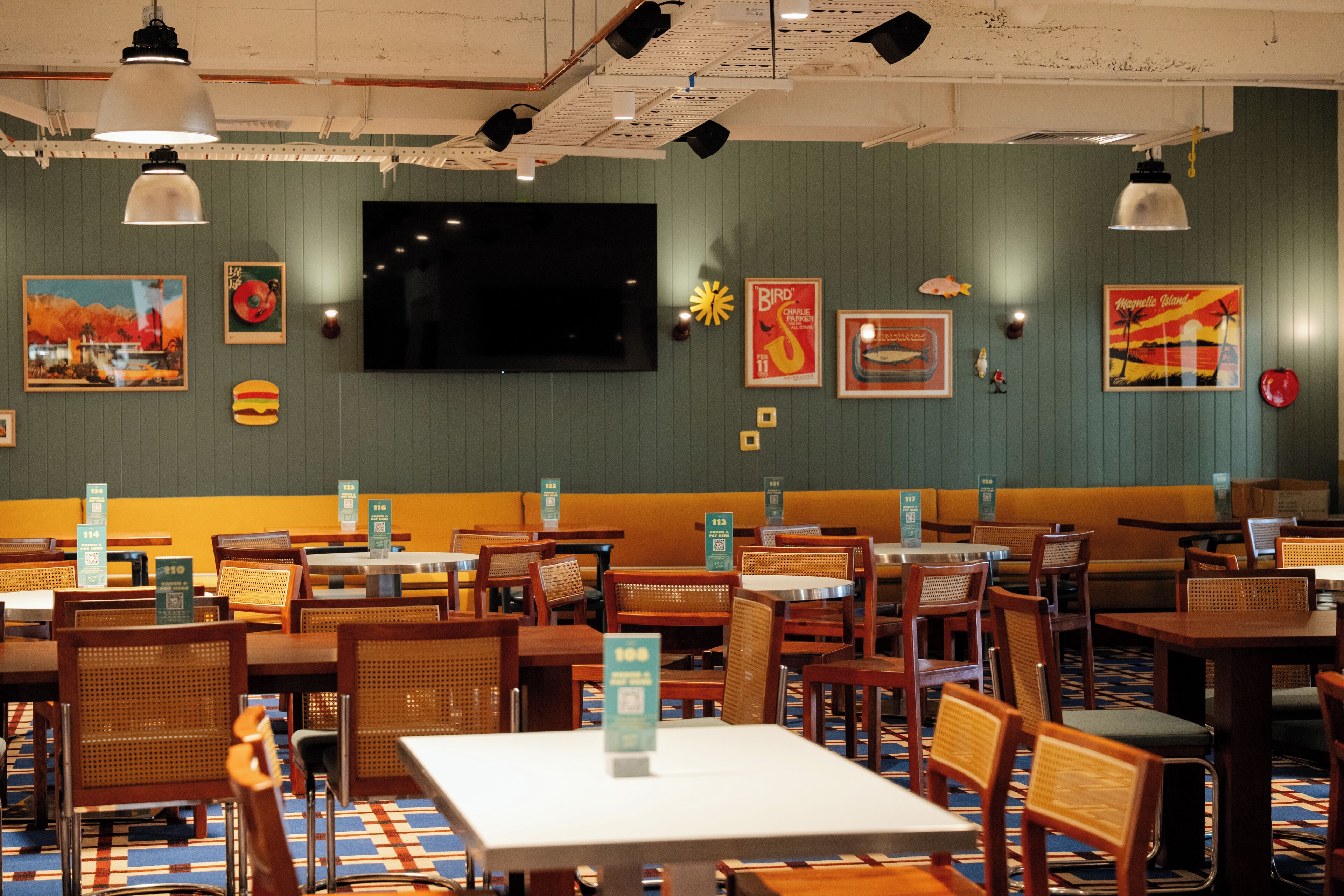 Un restaurante con cabinas y mesas, un televisor de pantalla plana y diversas decoraciones en las paredes.