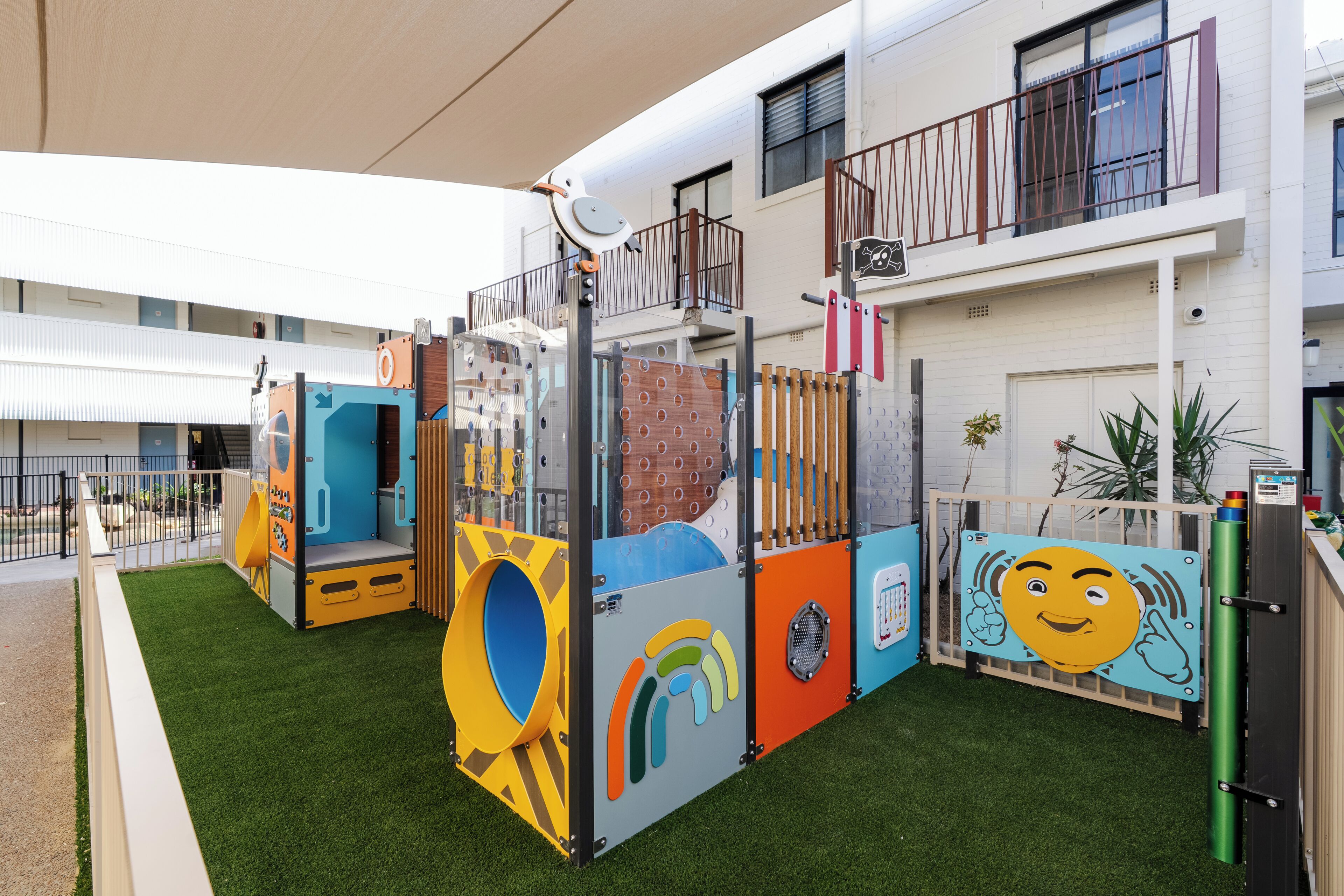 A children's play area with various play structures and a building in the background.