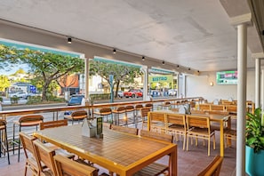Un caffè all'aperto con tavoli e sedie in legno, una insegna BISTRO e vista sulla strada.