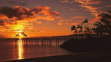A sunset over a body of water with a pier extending into the water.