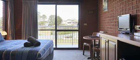 Een hotelkamer met een bed, een bureau, een televisie en uitzicht op het omliggende landschap.