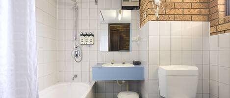 A bathroom with a bathtub, sink, toilet, and a hairdryer mounted on the wall.