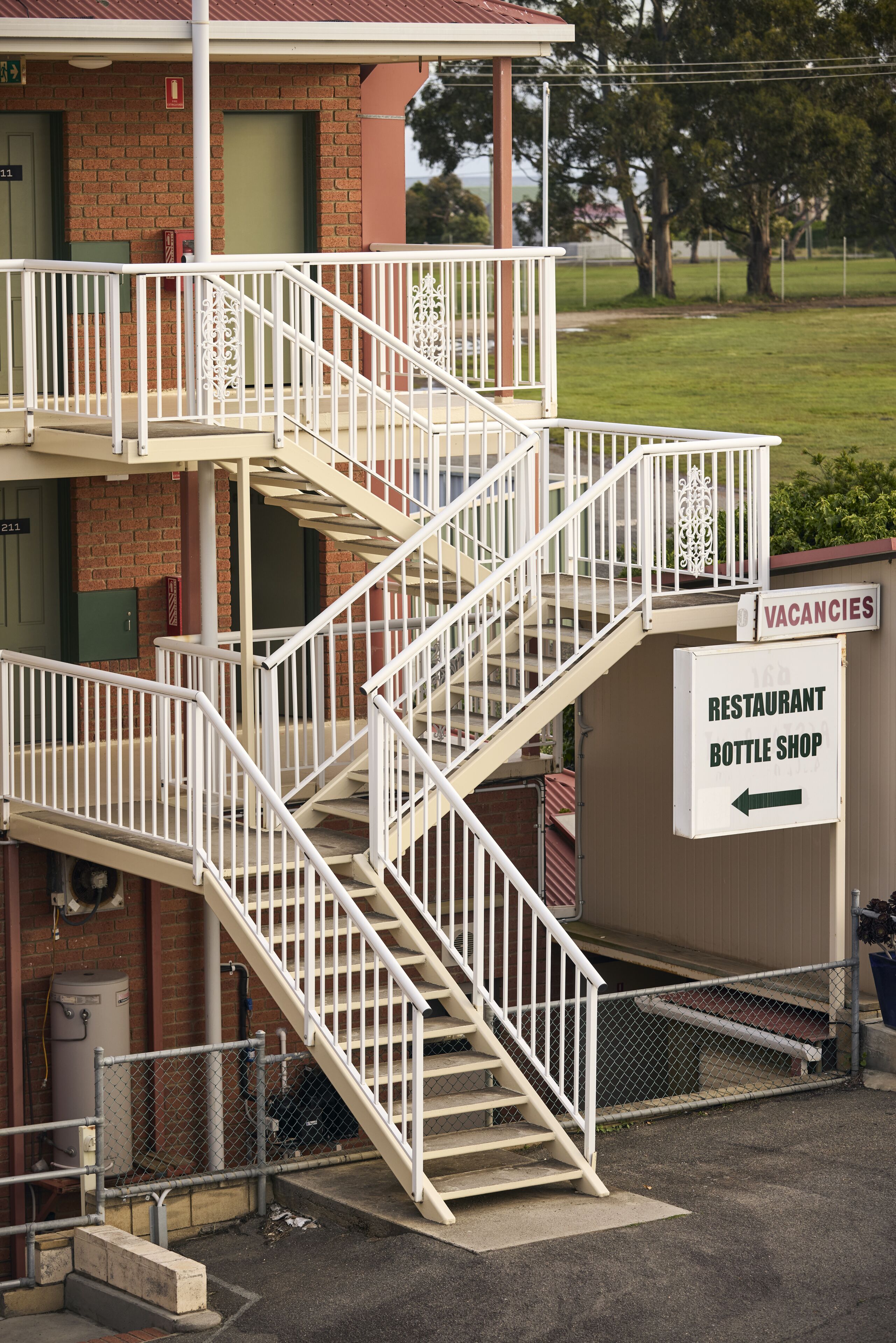 A multi-story building with a staircase, a sign indicating vacancies, and a sign for a restaurant and bottle shop.