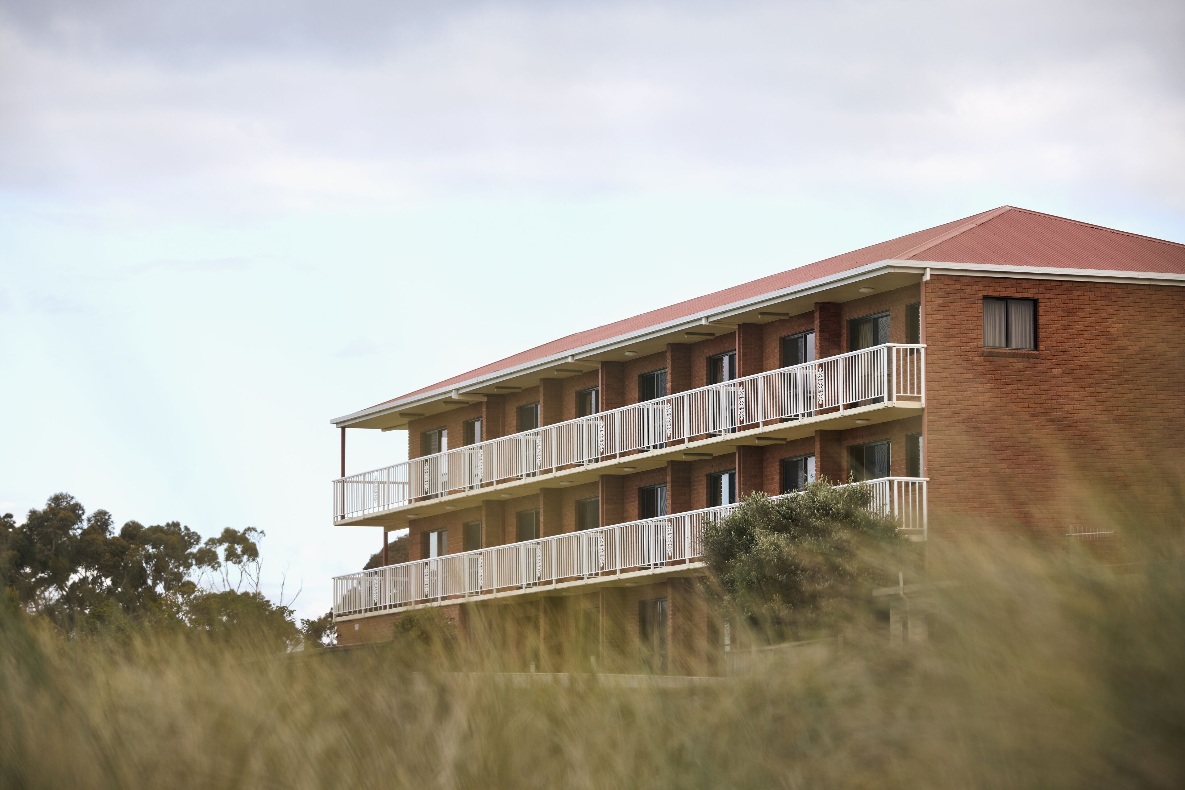 A multi-story building with a red roof and white balconies.