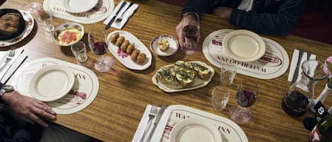 A dining table set with plates, glasses, cutlery, and a bottle of wine.