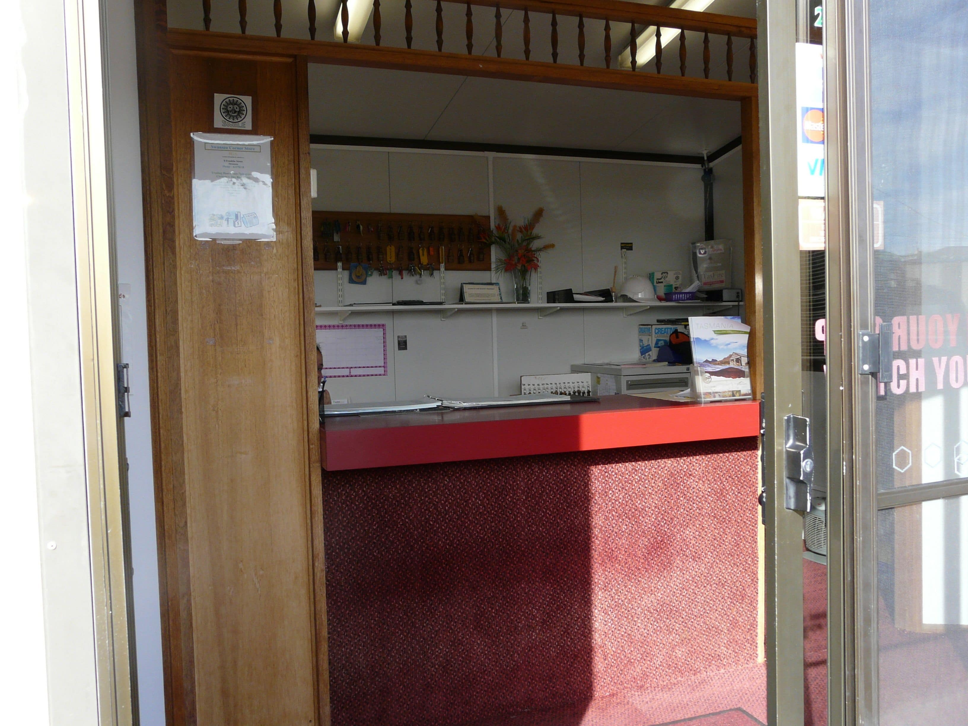 A reception area with a red counter, a wooden door, and a window with a view.