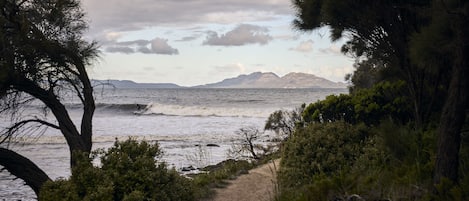 A coastal path with a view of the sea and distant mountains.