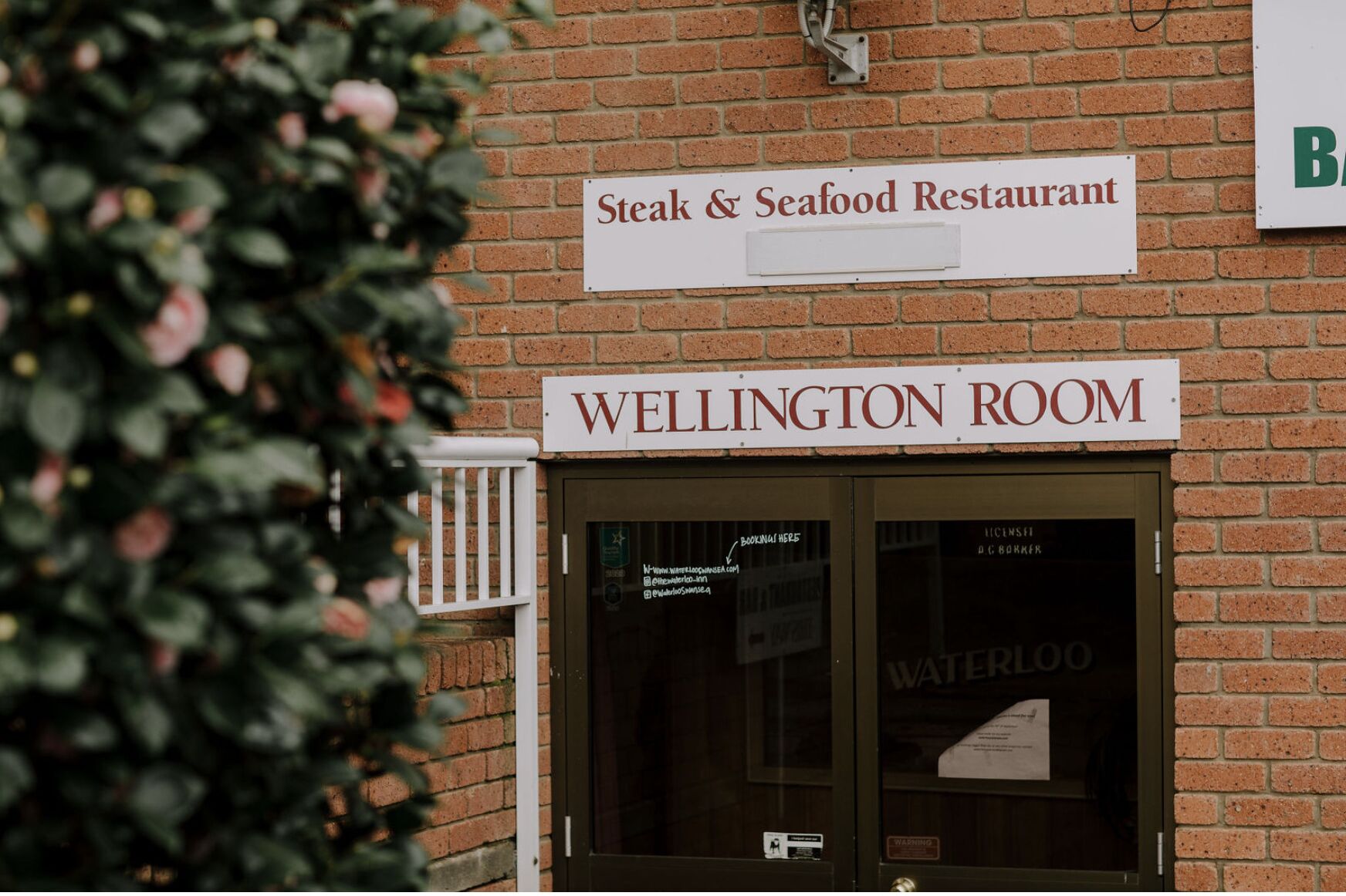 A brick building with a sign for 'Steak & Seafood Restaurant' and 'Wellington Room'.