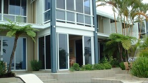 A modern house with a swimming pool, outdoor furniture, and tropical plants.