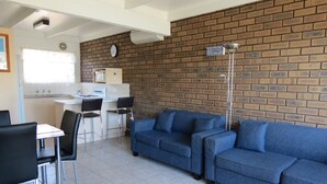 Eine moderne Küche mit Ziegelwand, ein Essbereich mit blauem Sofa und einer Uhr an der Wand.