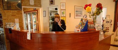 A reception desk with a wooden counter, a glass display case, and a vase with flowers.
