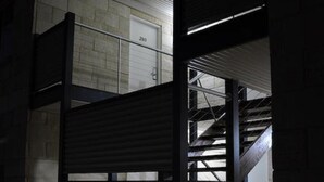 Un edificio con escaleras, una puerta de garaje y un pequeño jardín con un farol.