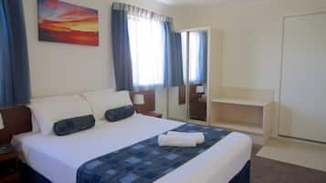 Una camera d'albergo con un letto, un comodino, una scrivania, uno specchio e una finestra con tende.