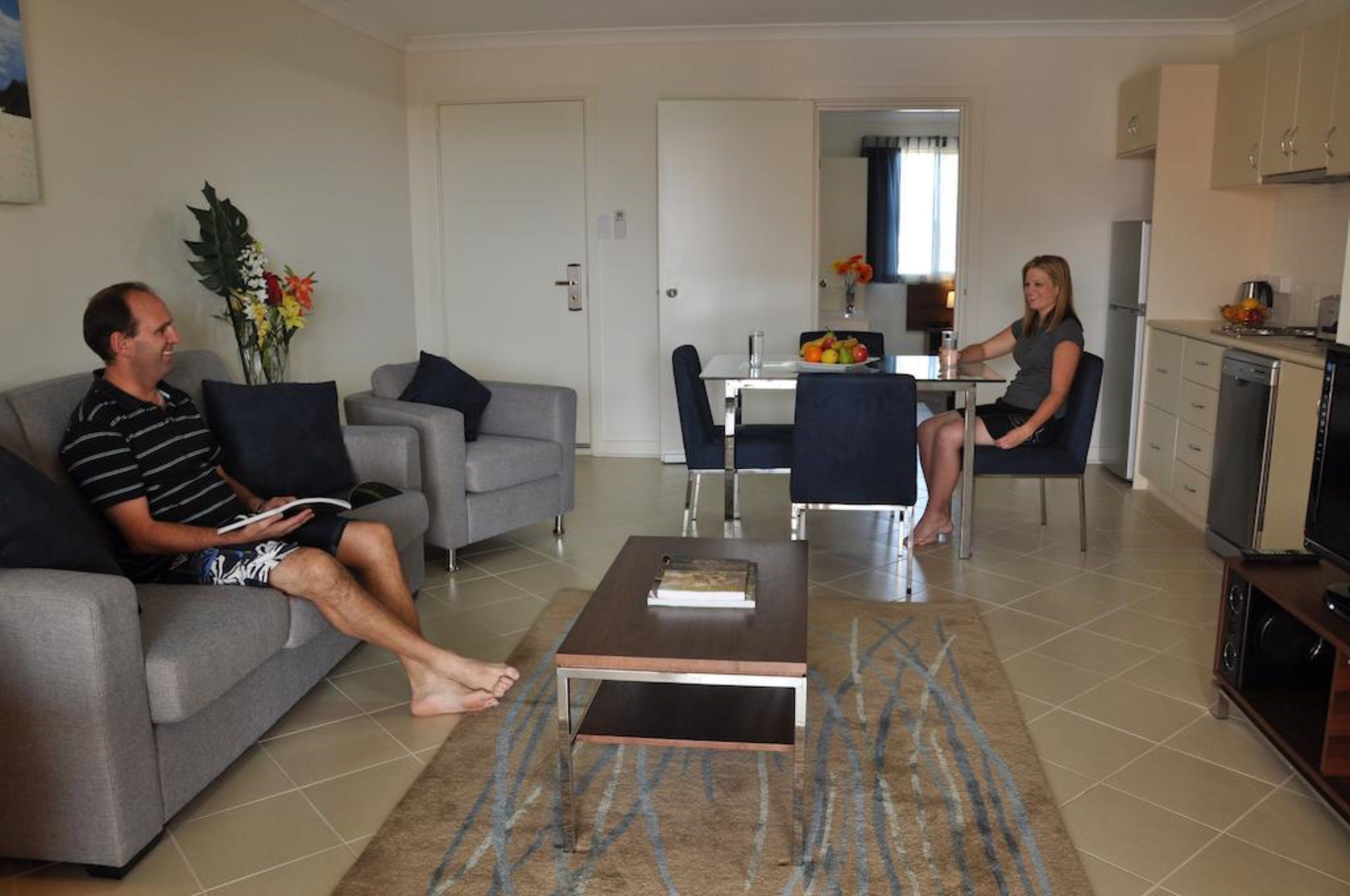 A living room with a sofa, a coffee table, and a dining area with chairs and a table.