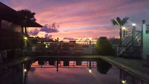 A pool area with a sunset view, a staircase, and a building in the background. - Patong Princess (Patong)