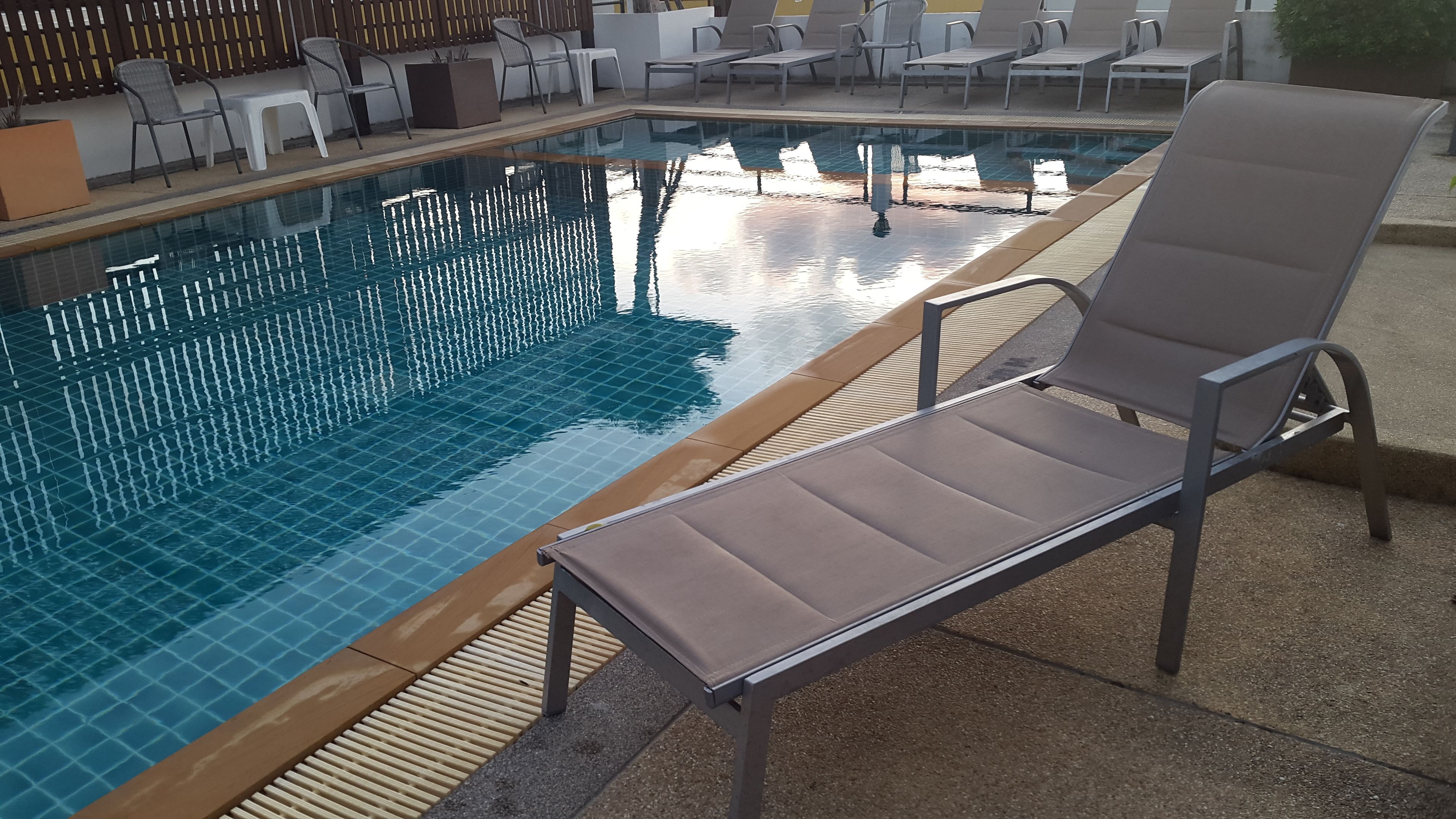 Una piscina al aire libre con sillones de descanso y un solárium con baldosas.