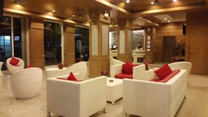 A spacious lobby with white wicker furniture and red cushions, large windows, and a reception desk. - Patong Princess (Patong)