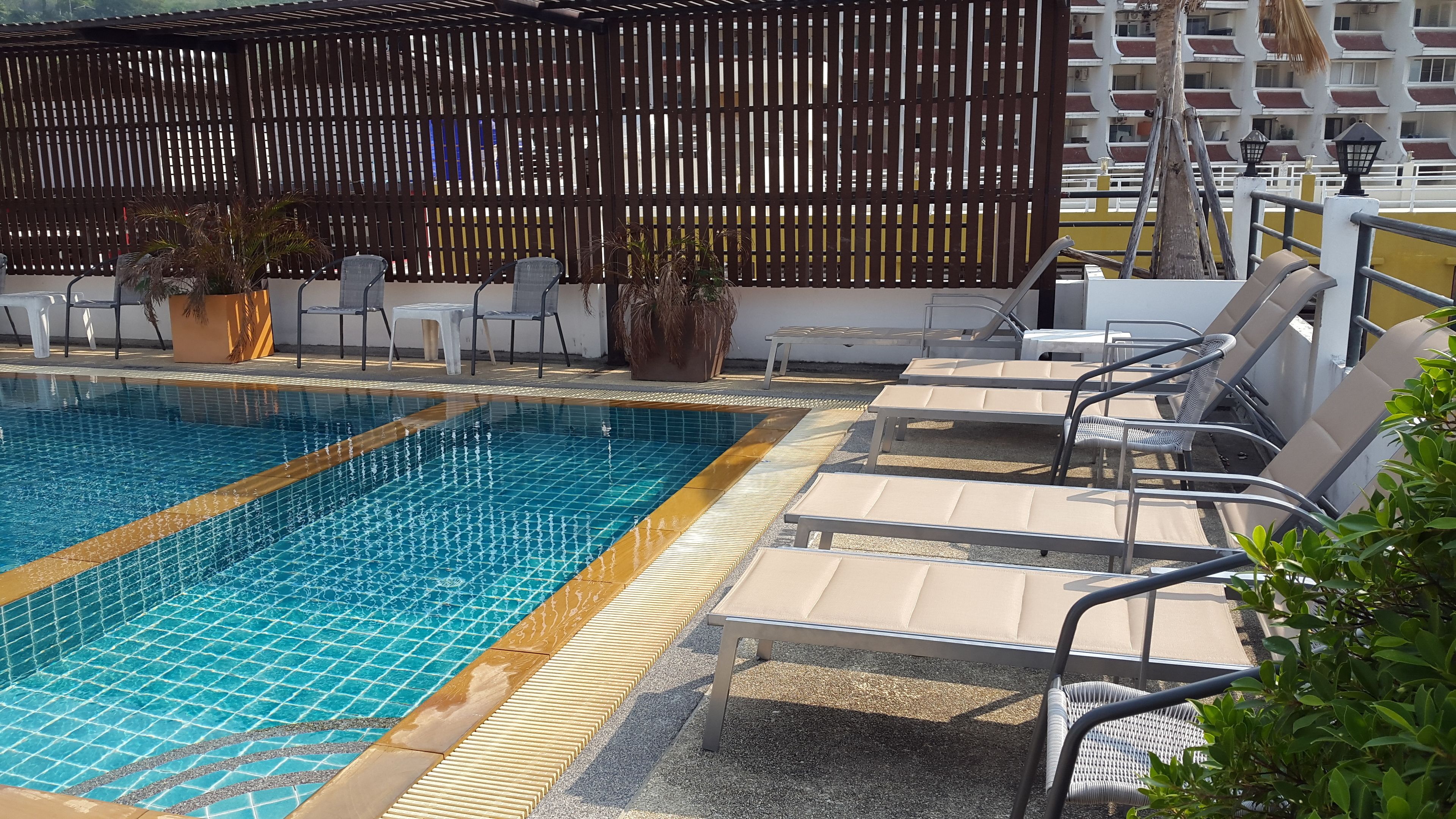 A swimming pool with lounge chairs and a wooden fence.