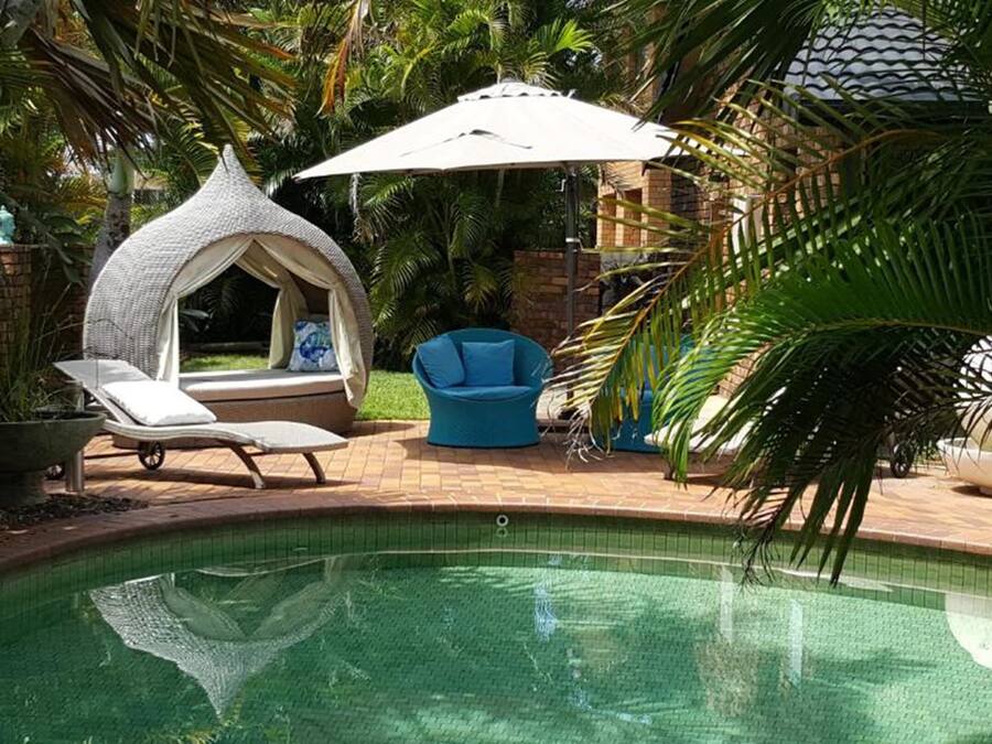 Un área de piscina con una silla de descanso, una silla azul y una zona de estar techada.