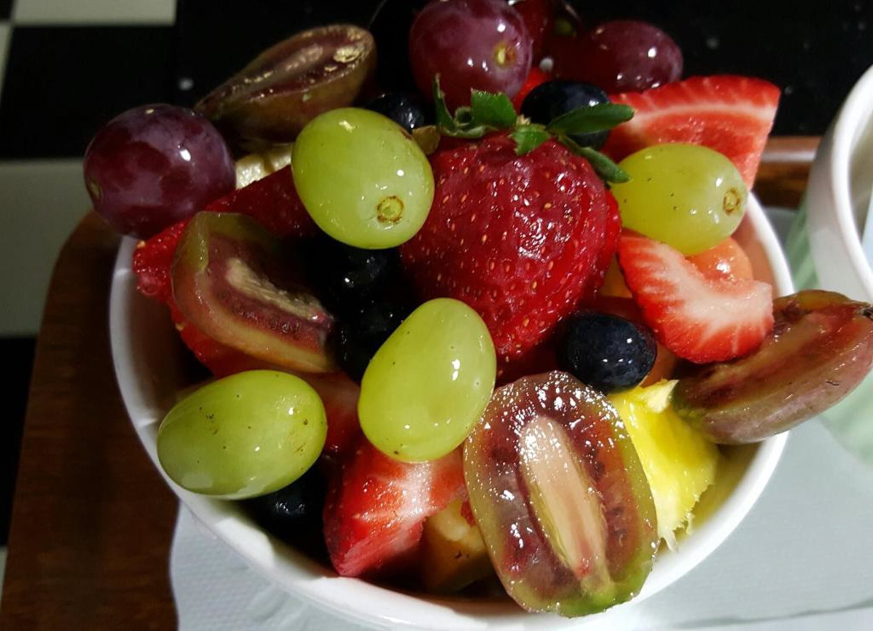 A bowl of mixed fruit including strawberries, grapes, and blueberries.