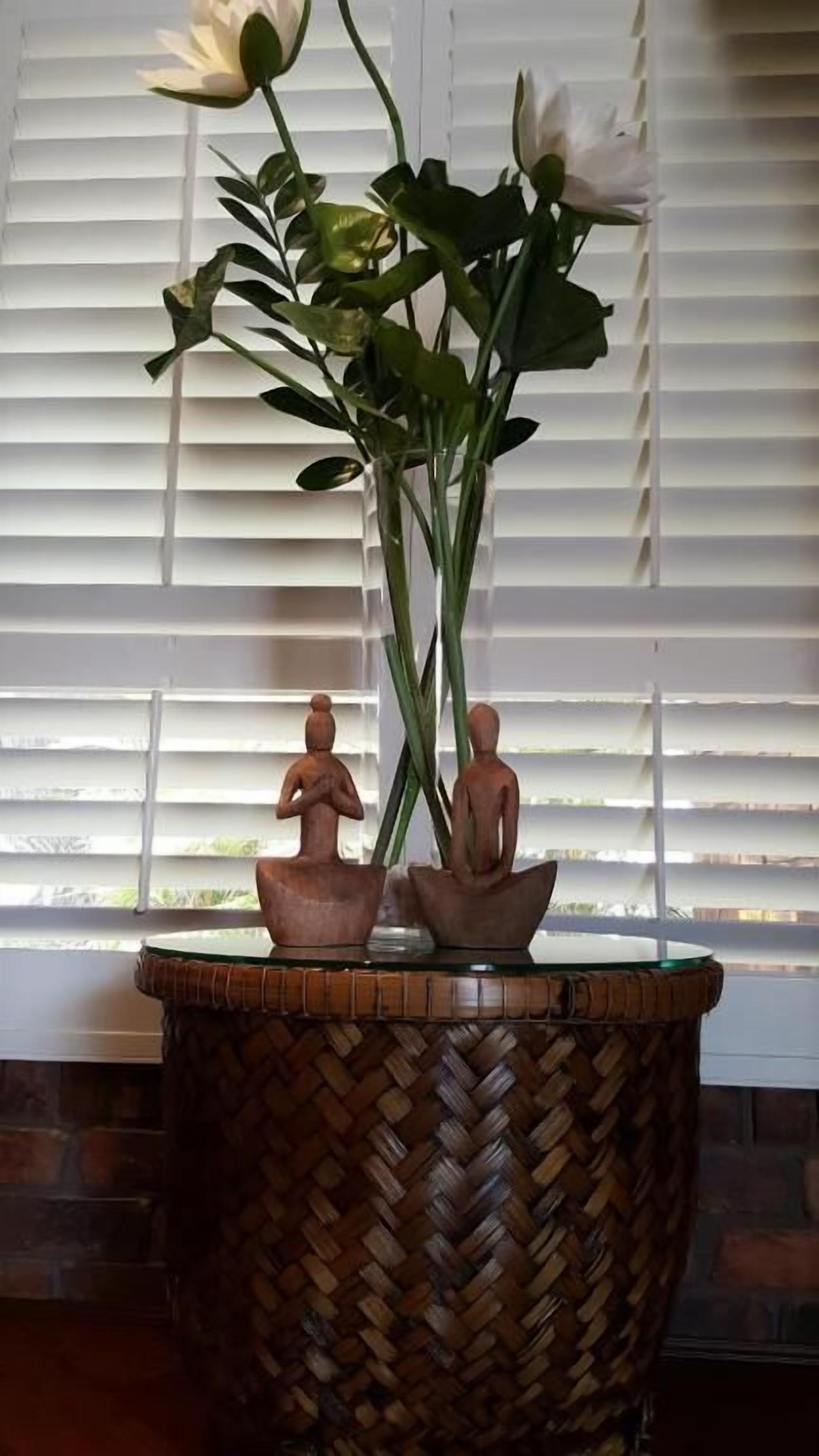 A woven basket with a vase containing a plant and two small figurines.