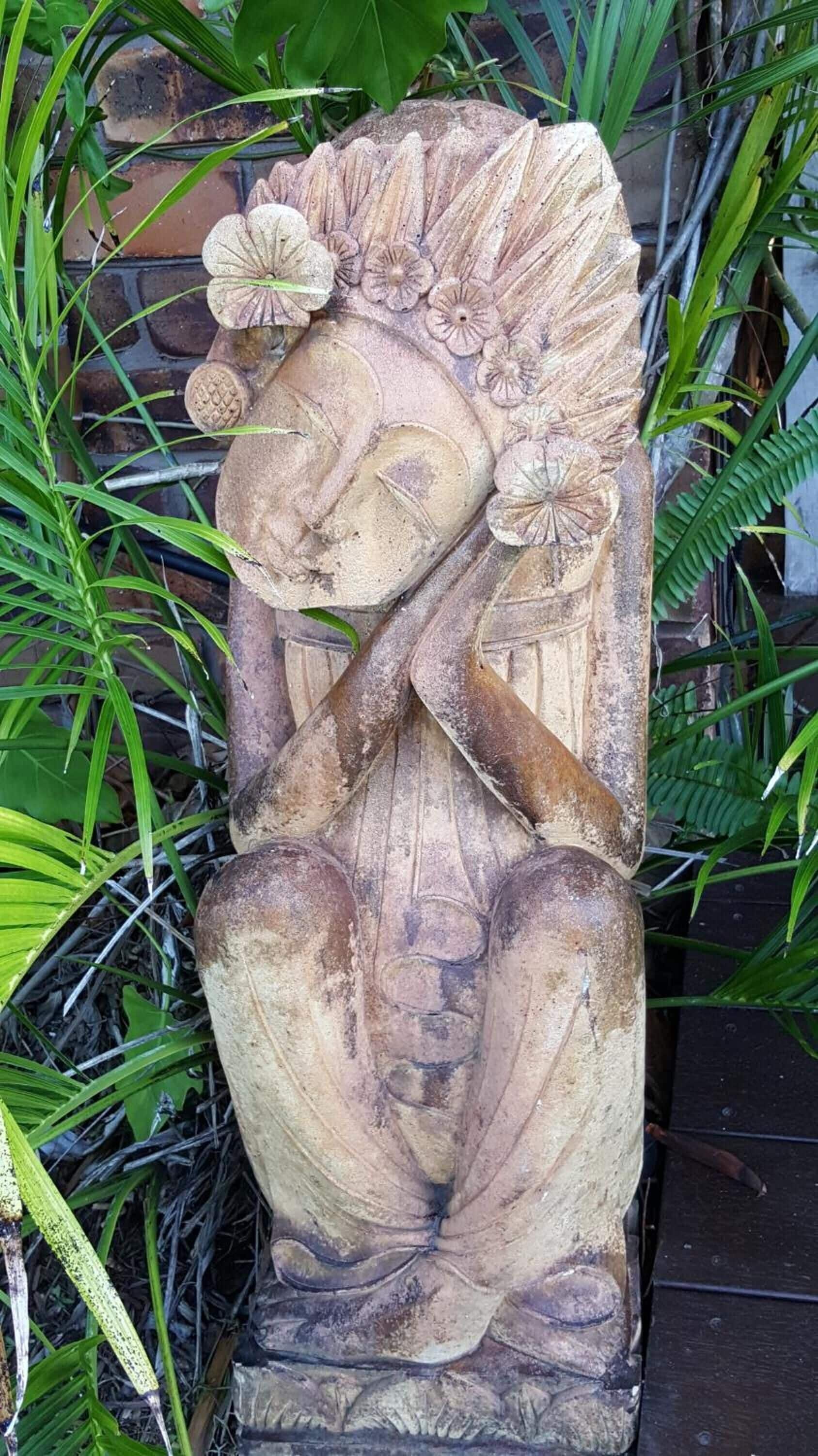 A stone sculpture with intricate carvings of a figure holding a staff, surrounded by foliage.