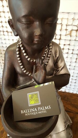 Une statue d’un enfant tenant une boîte sur laquelle est inscrit « Ballina Palms Boutique Motel ».