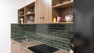 Una cocina con estufa negra, armarios de madera y salpicadero con azulejos verdes.