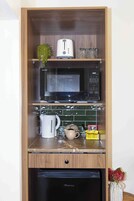 Una cocina compacta con microondas, tostadora y cafetera sobre la encimera.