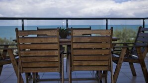 Una mesa y sillas de madera en un balcón con vista al océano.