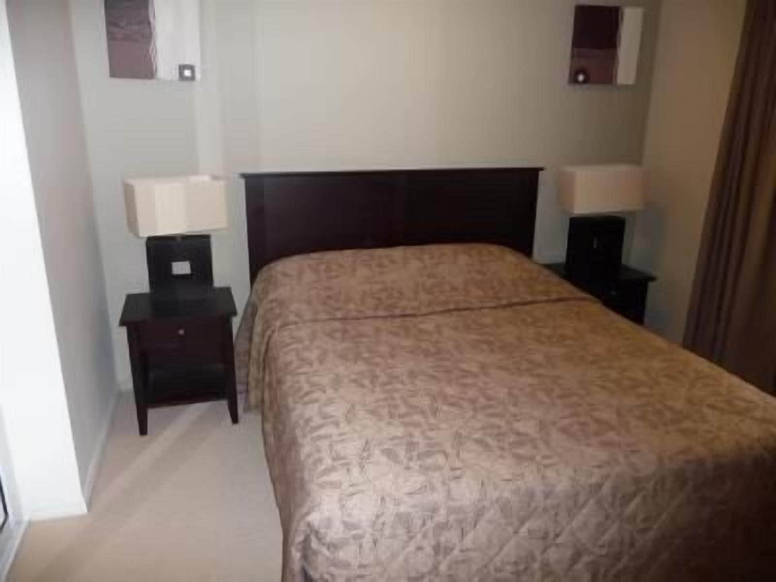 Ein Hotelzimmer mit einem Bett, zwei Nachttischen und einem Schranken.