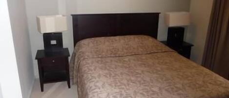 A hotel room with a bed, two bedside tables, and a nightstand.