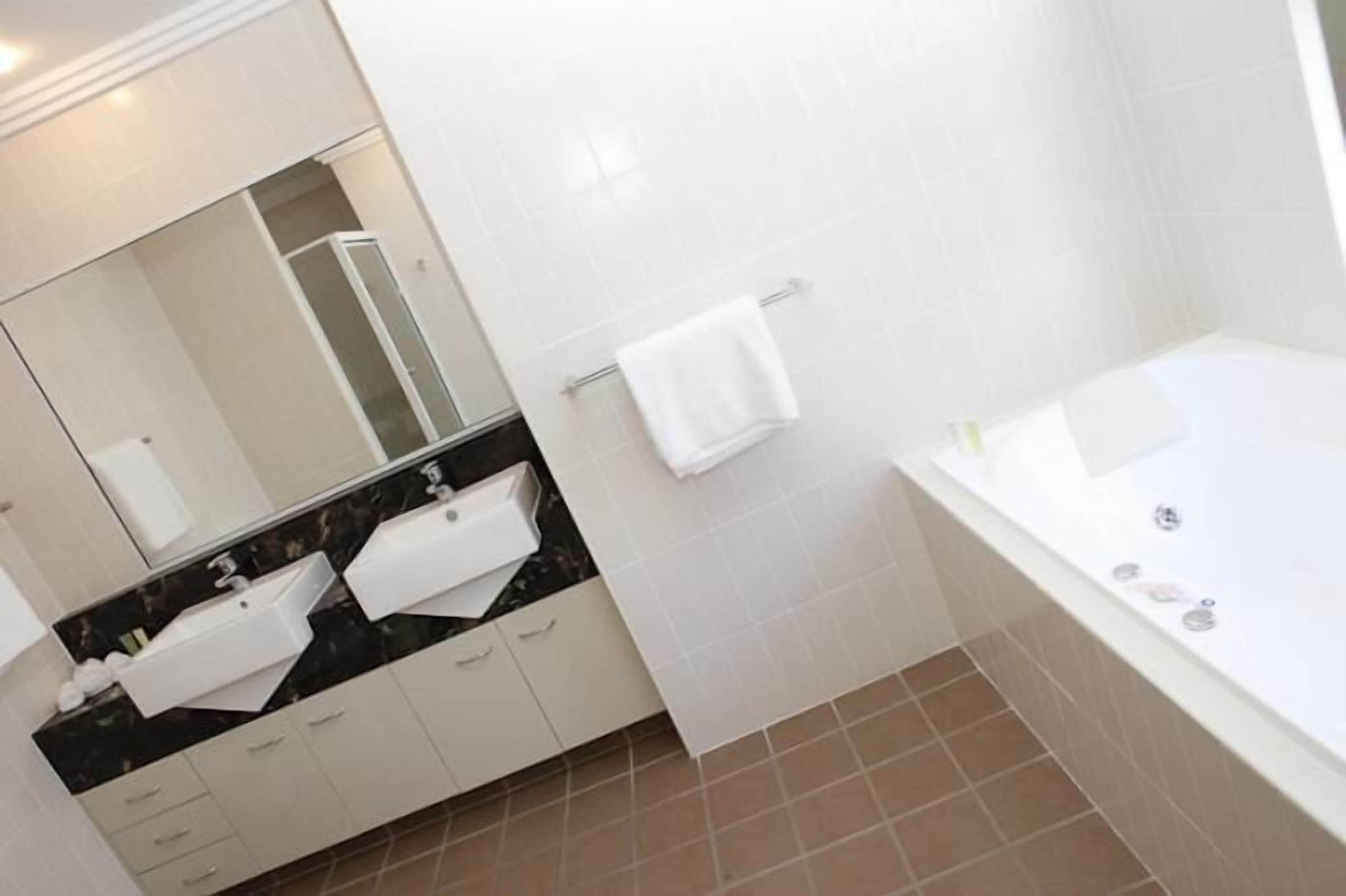 A modern bathroom with a bathtub, a vanity with a mirror, and a towel rack.