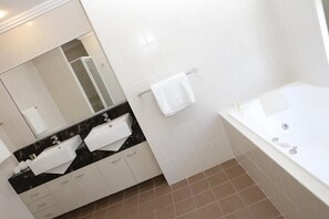 A modern bathroom with a bathtub, a vanity with a mirror, and a towel rack. - Pacific Reef by Kacys (Bargara)