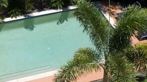 Una piscina rectangular rodeada de abundante vegetación y una cerca.