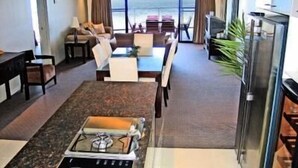 Una cocina moderna con estufa a gas, comedor con mesa y sillas, y vista al océano a través de amplias ventanas.